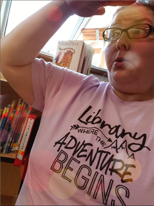 Mrs. Sand, with her hand over her head, searching for awesome library books in the distance. 